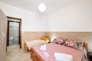 A bedroom with two beds, a bathroom, and a wooden door. - Villa Benedetta 50m From Beach (Lecce)