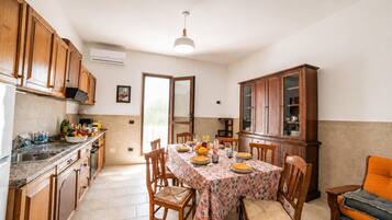 Una cocina con armarios de madera, una mesa de comedor para cuatro personas y un aparador con puertas de vidrio.