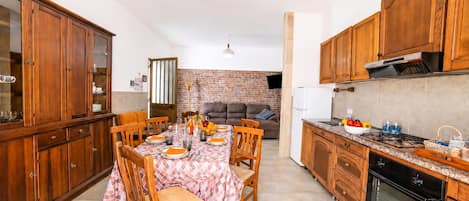 Una cocina con armarios de madera, una mesa de comedor preparada para cuatro personas y una pared de ladrillo al fondo.