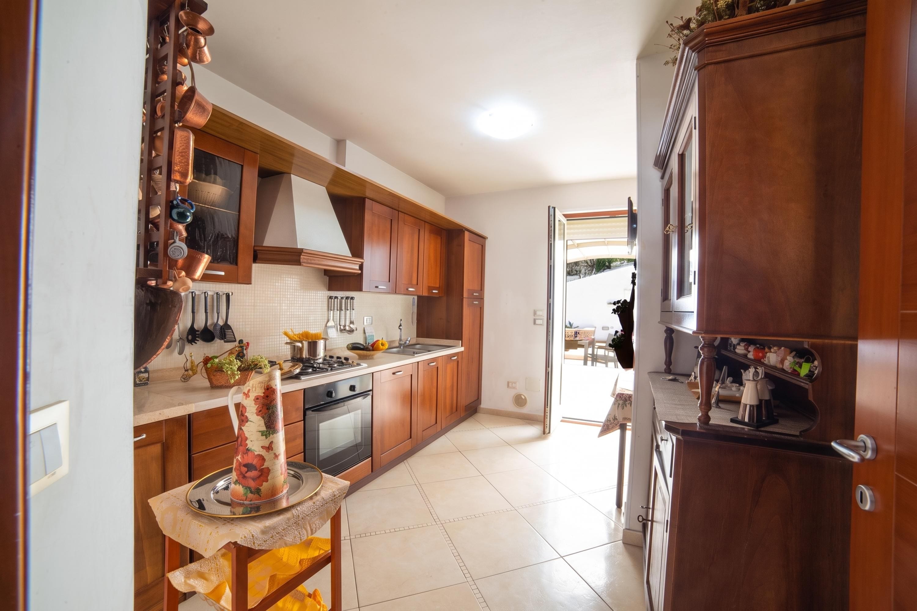 A kitchen with wooden cabinets, a stove, and a sink.