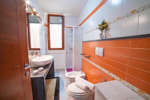A bathroom with a double sink, a toilet, and a shower.