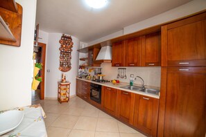 Une cuisine avec des meubles de rangement en bois, une cuisinière, un évier et un élément décoratif mural.