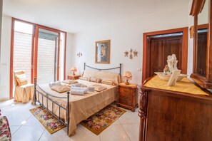 Une chambre à coucher avec un lit, une table de chevet, une commode, un miroir et une fenêtre.