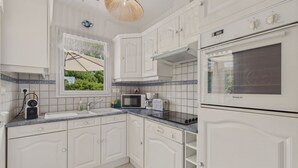 A modern kitchen with white cabinetry, a built-in oven, a microwave, and a sink.