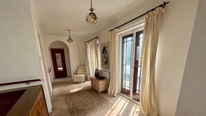 A spacious room with a large window, a wooden bench, a small table, and a chair.