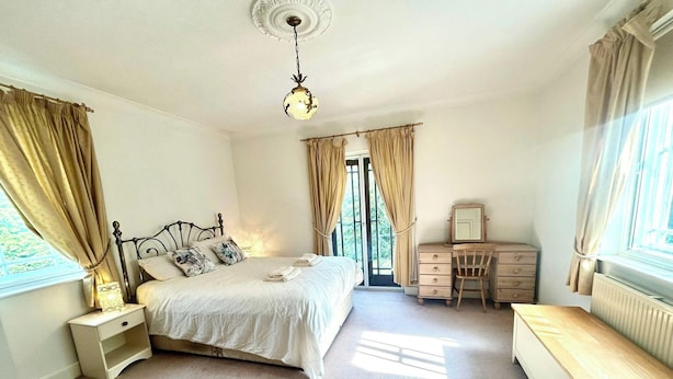 A bedroom with a bed, bedside table, dresser, chair, and a desk.