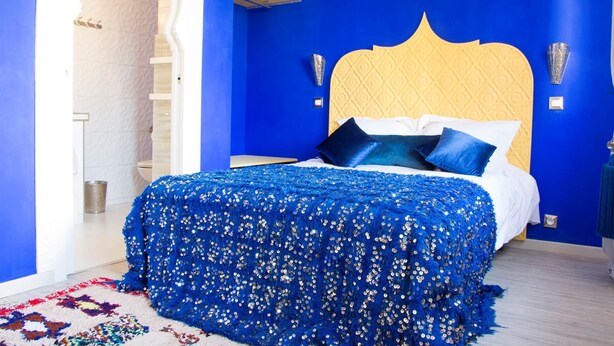 A bedroom with a blue wall, a yellow headboard, and a patterned bedspread. - Majorelle (Tours)