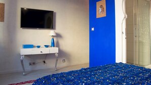 A room with a white vanity, a flat-screen TV, and a blue accent wall. - Majorelle (Tours)