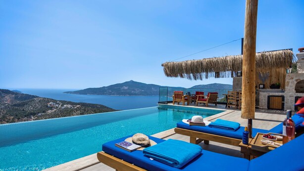 A poolside area with lounge chairs and a view of the sea. - Rustic Villa Perfect for Couples (Bezirgan)