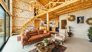 A spacious living area with a stone wall, wooden staircase, and a large window. - Rustic Villa Perfect for Couples (Bezirgan)