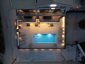 An aerial view of a rooftop pool area with a rectangular pool, surrounded by seating and a small deck. - ZEN BLU Suites  (Nikiana)