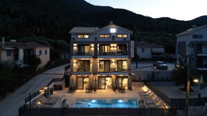 A two-story building with a swimming pool, outdoor seating, and a view of the surrounding hills. - ZEN BLU Suites (Nikiana)