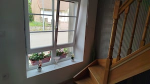 A room with a large window, a wooden staircase, and a small table with potted plants.