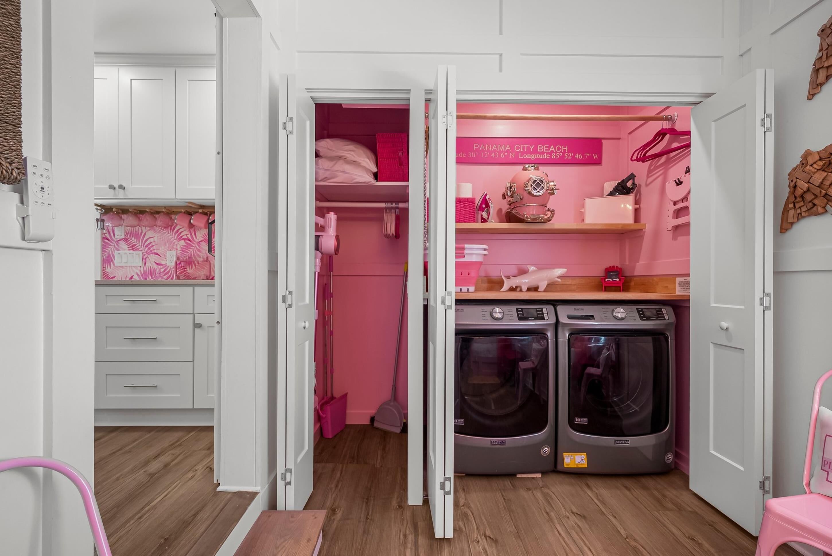 Un cuarto de lavandería con dos lavadoras, un tendedero y un estante con diversos objetos.