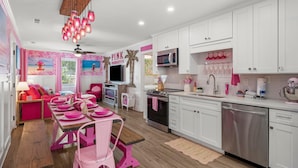 A modern kitchen with white cabinets, stainless steel appliances, and pink accents. - Beach House - Pink Prerogative by PHG (Panama City Beach)