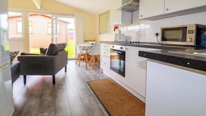 Una cocina moderna con armarios blancos, un microondas y un comedor con mesa y sillas.