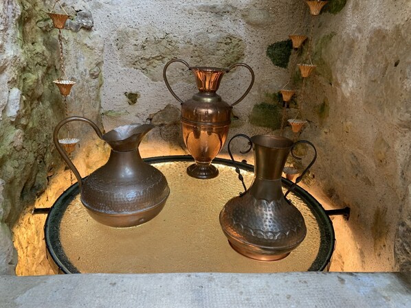 A display of copper vases on a textured wall.