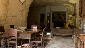 A rustic dining area with a stone wall, wooden table, chairs, and a chandelier. - Leonardo at our 'Clos Lussault' near Amboise in the Loire Valley (Lussault-sur-Loire)