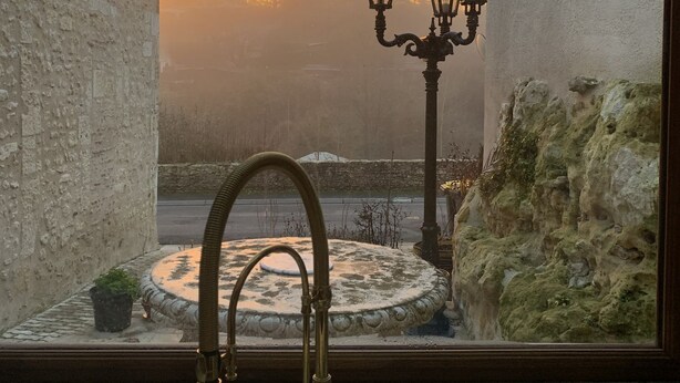 A view from a window overlooking a courtyard with a fountain, two street lamps, and a stone wall. - Leonardo at our 'Clos Lussault' near Amboise in the Loire Valley (Lussault-sur-Loire)