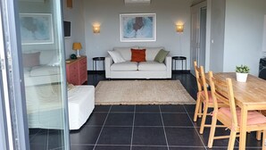 Ett modernt vardagsrum med en soffa, ett matbord med stolar, en matta och en stor tavla på väggen.