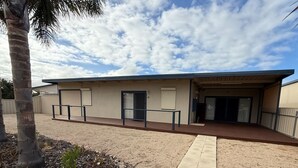 A building with a flat roof, a covered entrance, and a paved walkway leading to it.