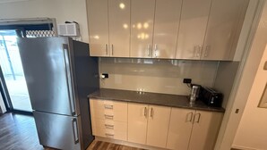 A modern kitchen with light wood cabinets, a stainless steel refrigerator, and a toaster on the countertop.