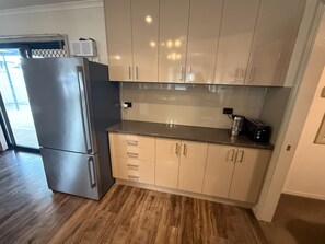 A modern kitchen with light wood cabinets, a stainless steel refrigerator, and a toaster on the countertop. - Shore Beats Work - Large entertaining area! Dog friendly! (Stansbury)