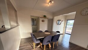 A modern kitchen with a dining area, wooden flooring, and a view through the door.