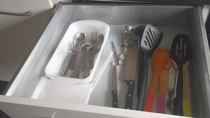 Un cajón con varios utensilios de cocina, incluyendo cucharas, tenedores, cuchillos y espátulas.