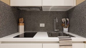 A modern kitchen with a black countertop, white cabinets, and a speckled backsplash. - Chic Trieste Gem (Trieste)