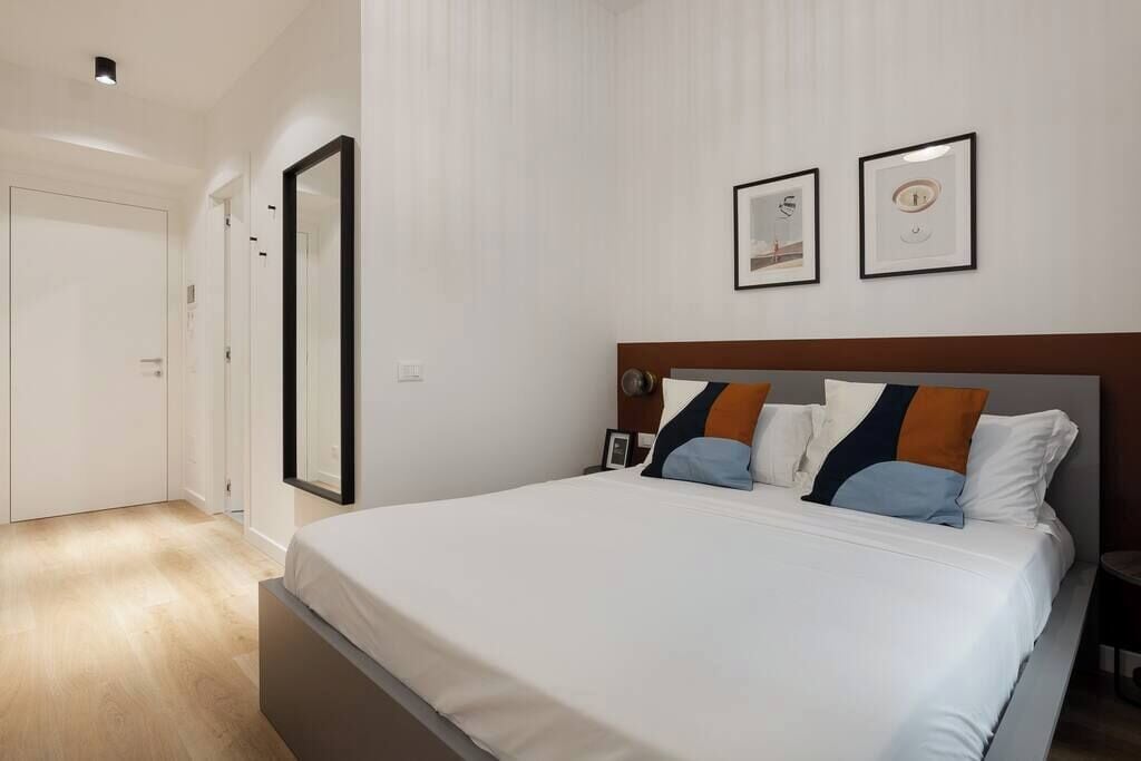 A hotel room with a large bed, a wooden headboard, and two framed pictures on the wall.