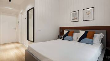A hotel room with a large bed, a wooden headboard, and two framed pictures on the wall.