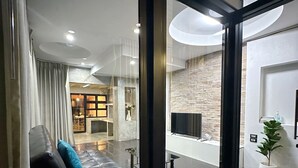 En modern hotellobby med ett rutmönstrat golv, en lädersoffa med kuddar, en vägg av sten och en platt-TV som är monterad på väggen.