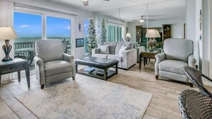 A living room with a sofa, armchairs, a coffee table, and a view of the ocean. - Bayfront Kontiki 107 (Rockport)