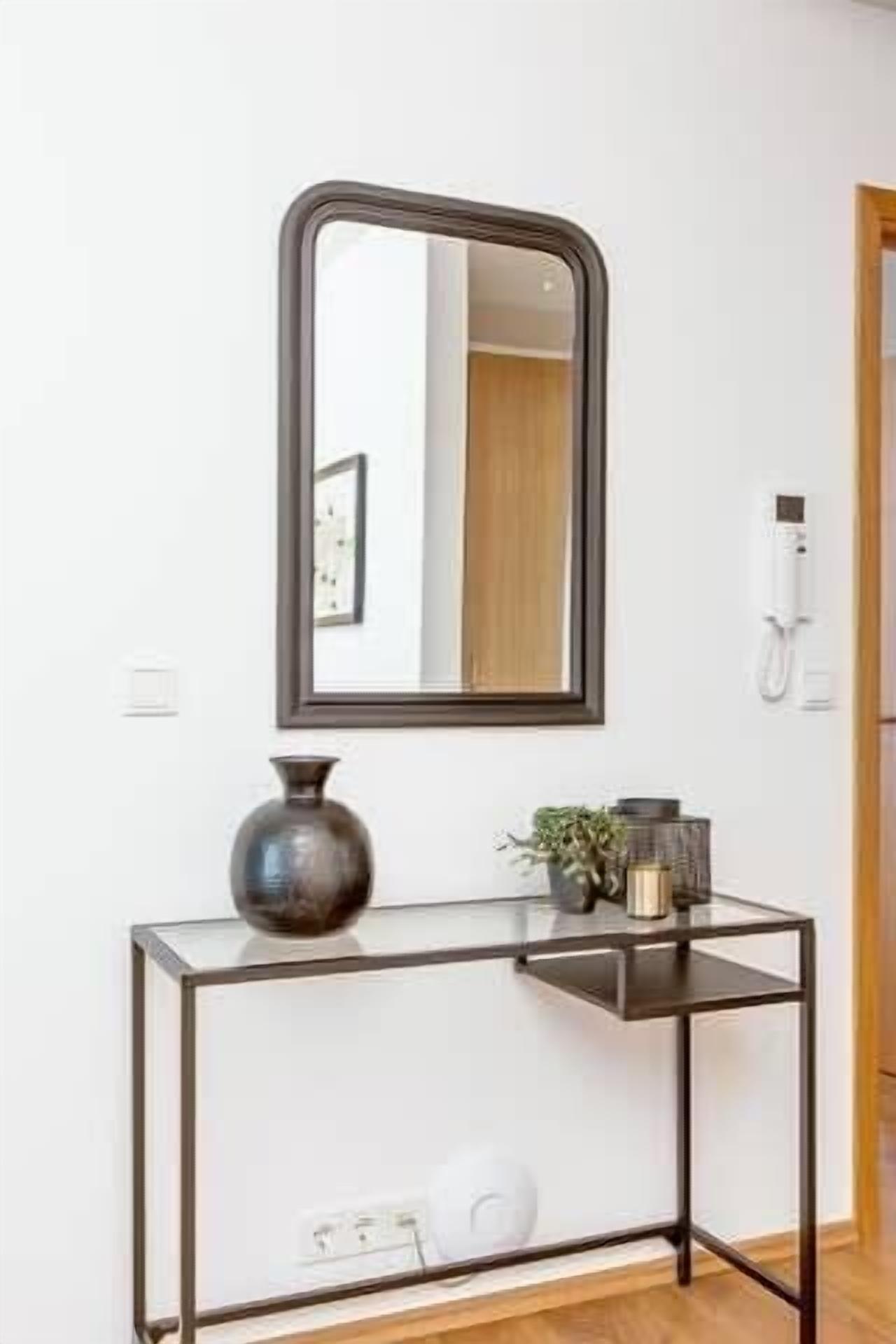 A modern console table with a mirror, a vase, and a small plant.