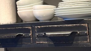 Un depósito de almacenamiento con una pila de cuencos, platos y un recipiente cilíndrico blancos.