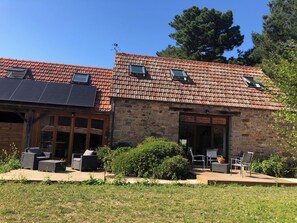 A stone building with a tiled roof, two skylights, and a deck with outdoor furniture.
