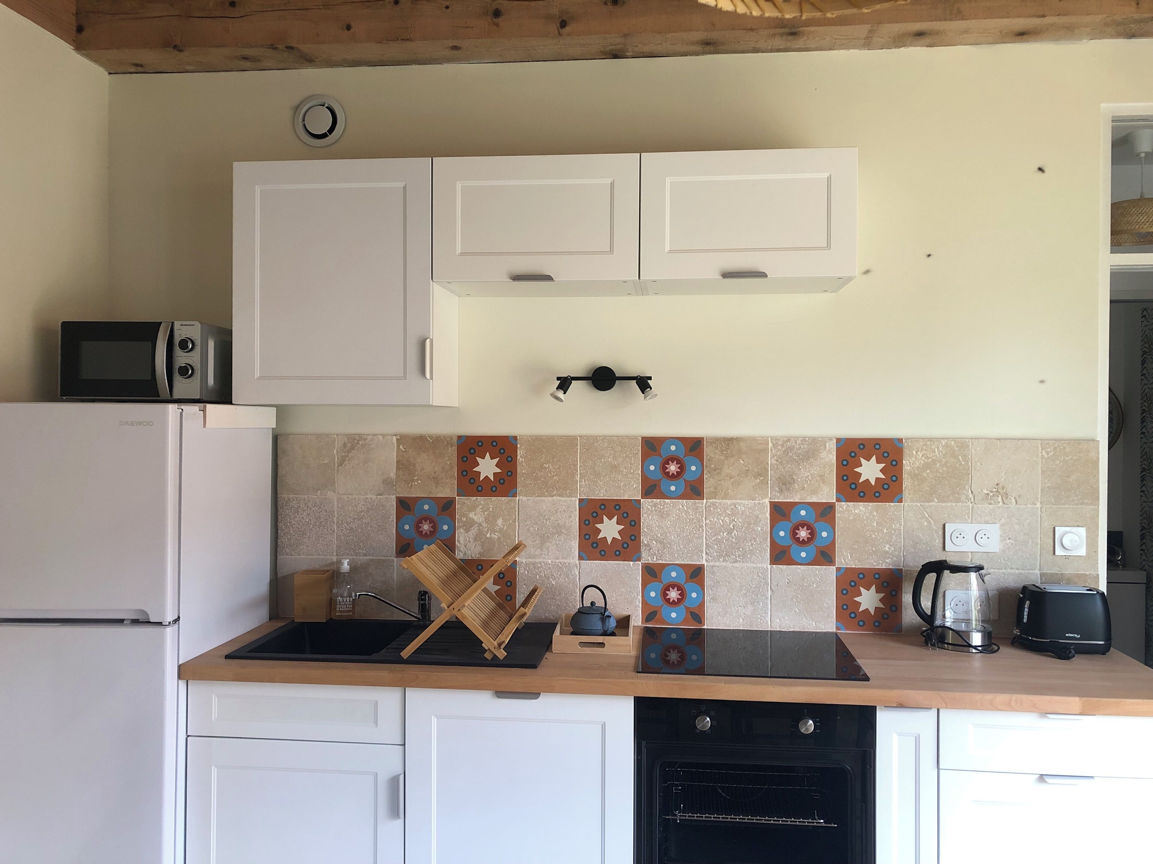 A kitchen with white cabinets, a microwave, a toaster, a kettle, and a coffee maker.