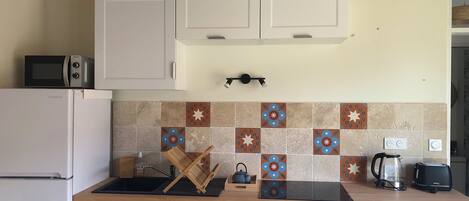 A kitchen with white cabinets, a microwave, a toaster, a kettle, and a coffee maker.