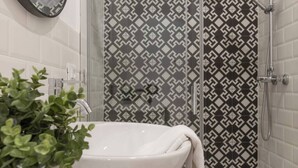 A bathroom with a white sink, a mirror, and a shower with patterned tiles. - Trieste Tranquil Tiny Haven (Trieste)