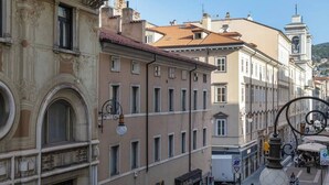 A street view with historic buildings, a pedestrian crossing, and a large spherical sculpture. - Trieste Tranquil Tiny Haven (Trieste)