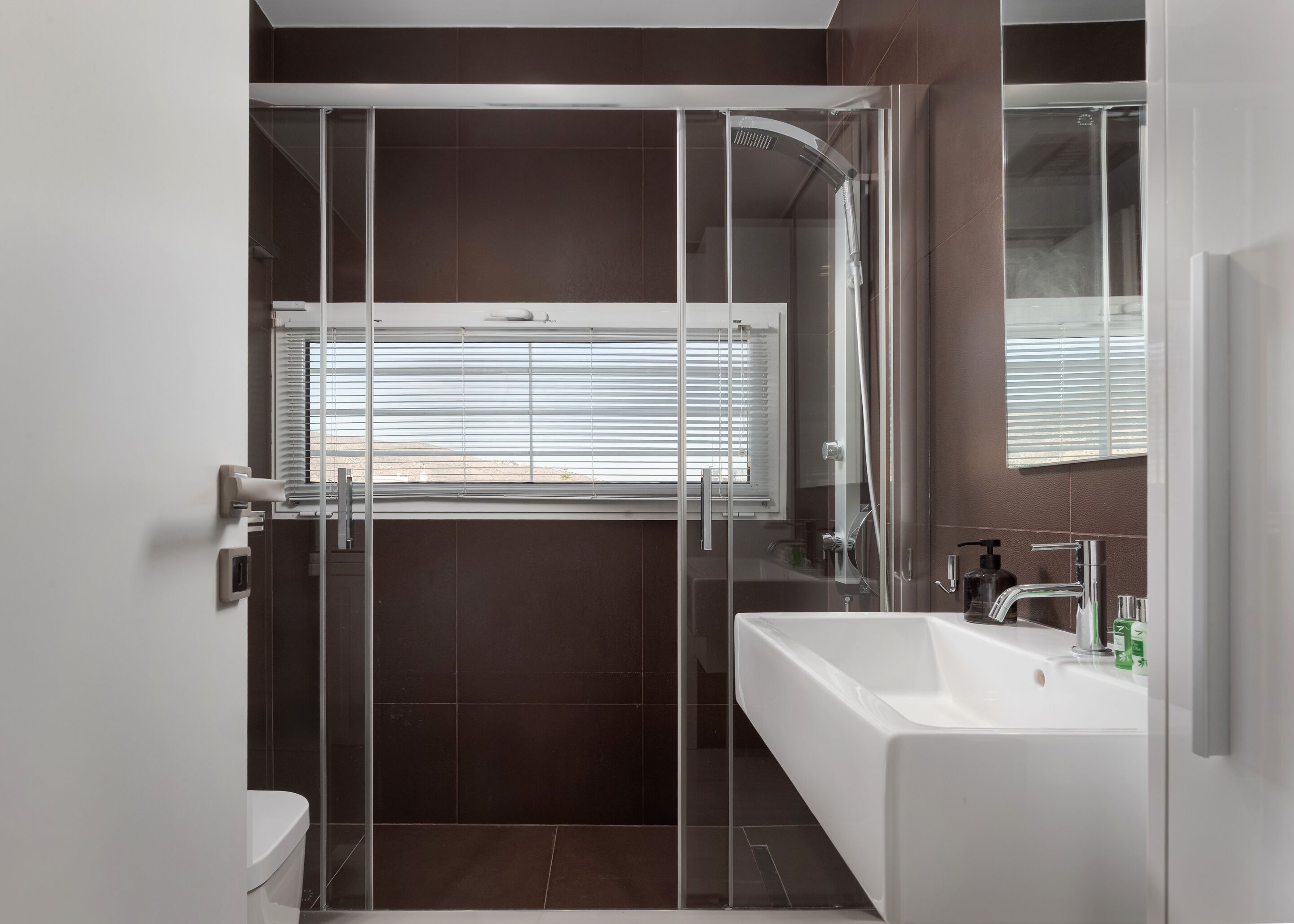 A modern bathroom with a glass-enclosed shower, a white bathtub, and a large mirror.