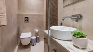 Une salle de bain moderne avec un lavabo, des toilettes et une douche, le tout de couleur blanche.