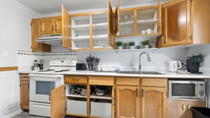 Una cocina moderna con armarios de madera, horno empotrado, microondas y un lavaplatos.