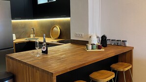 Une cuisine moderne avec un îlot central en bois, des tabourets de bar, un évier et une machine à café.