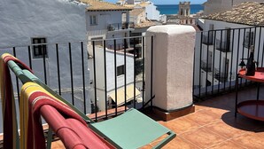 Une terrasse avec vue sur la mer, comprenant une table et des chaises, un pilier blanc et une balustrade.