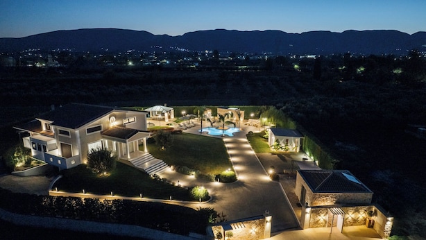 Ein modernes, mehrgeschossiges Haus mit Swimmingpool, gut beleuchteten Wegen und einem angelegten Garten.