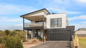 A modern two-story house with a balcony, large windows, and a garage. - Surf Mist at Surf Beach (Surf Beach)