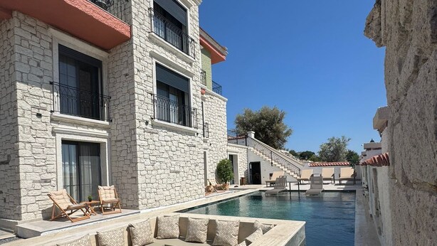 Un edificio de piedra con piscina y zona de estar exterior.