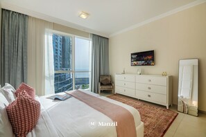 A hotel room with a large bed, a dresser, a chair, a TV, and a view of the city.